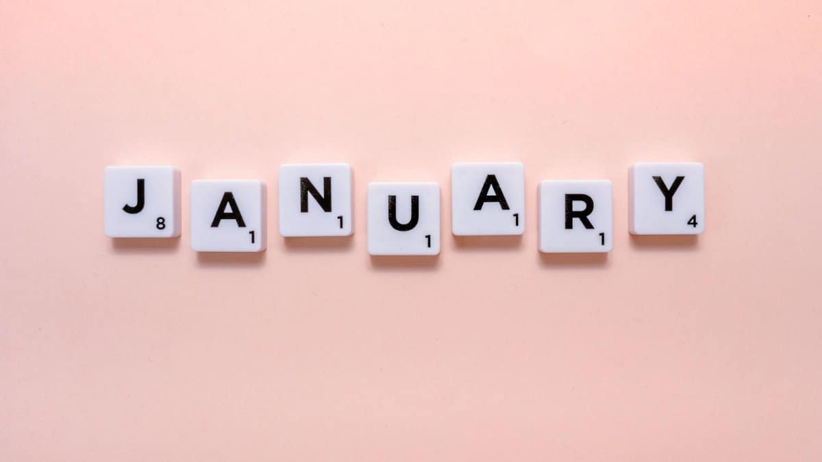 Scrabble tiles spelling 'January' on a soft peach background, perfect for new year themes.