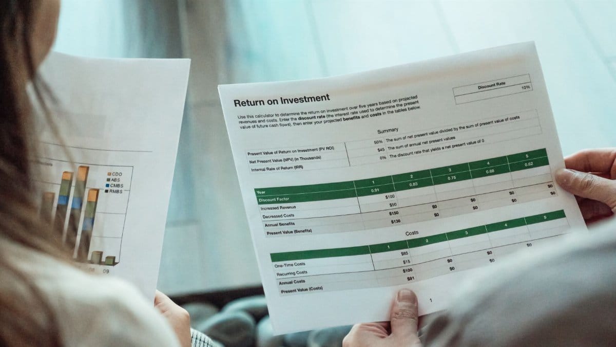Close-up of two individuals analyzing financial documents related to return on investment.