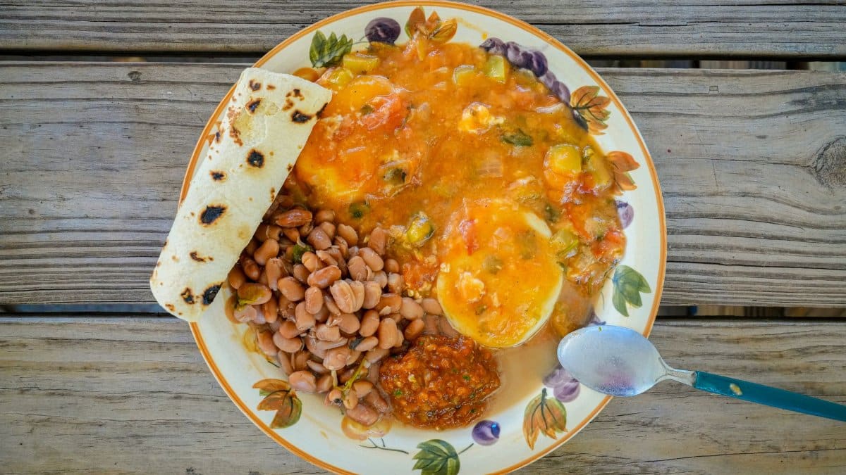 Delicious traditional Tex-Mex breakfast featuring eggs, beans, salsa, and tortilla on a rustic wooden table.