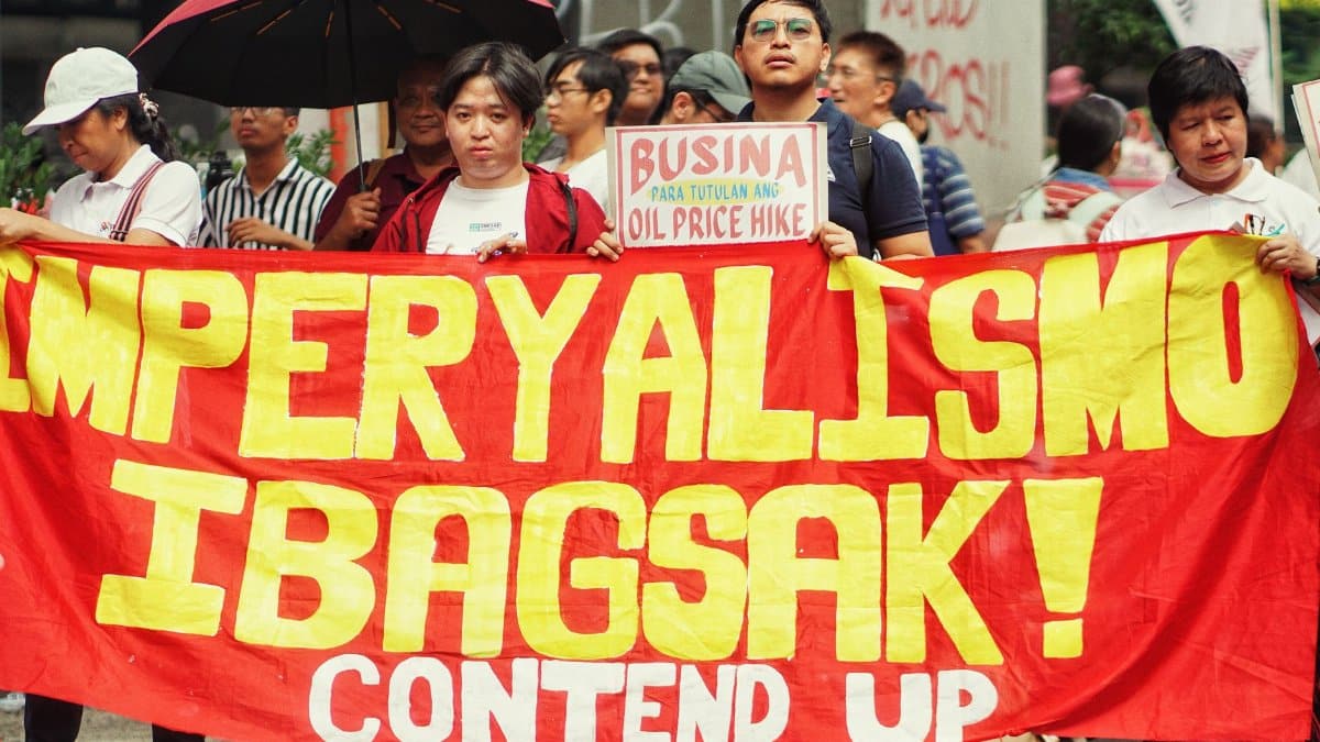 Protesters holding a bold anti-imperialism banner during a street demonstration.