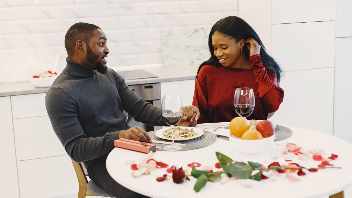 Couple enjoying a romantic dinner at home with wine and flowers.
