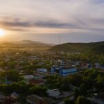 A breathtaking aerial view of an urban area with lush greenery and mountains at sunrise.