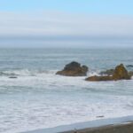Serene ocean view capturing waves and rock formations along the Klamath coast, California.