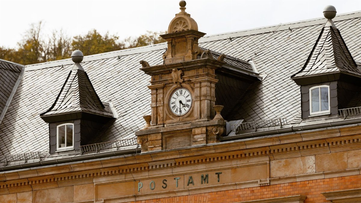 Close-up of the classic clock and rooftop of the historic post office in Eisenach, Germany.