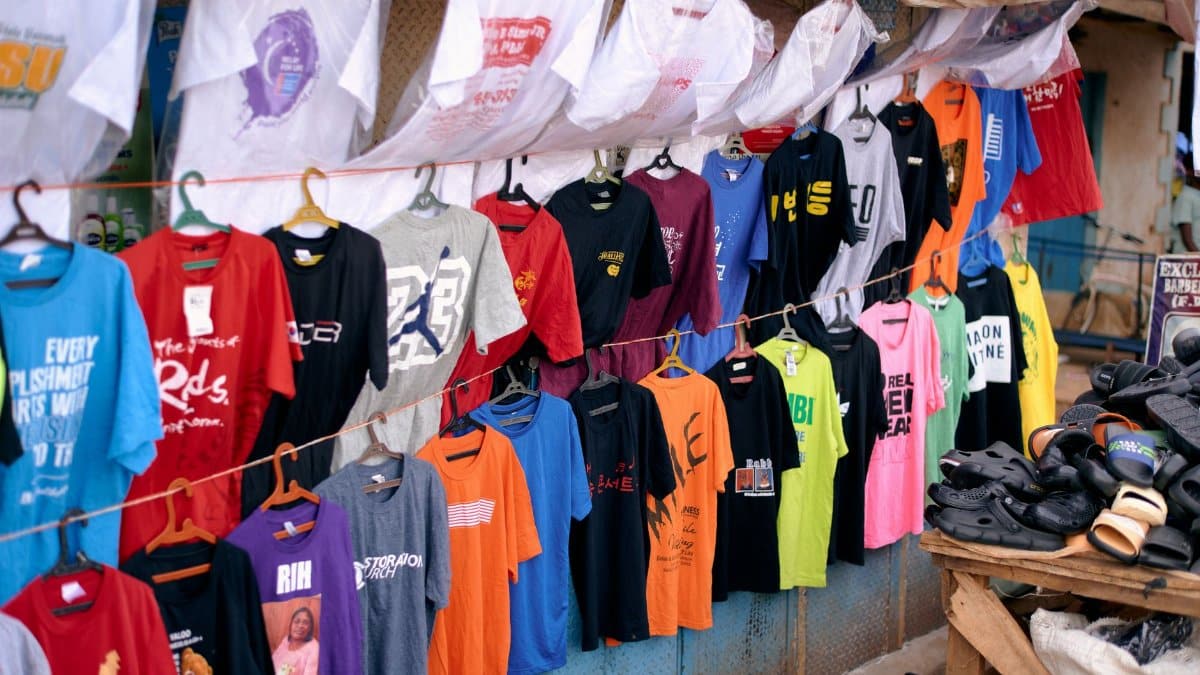 Vibrant collection of T-shirts and shoes on display at an outdoor market stall in Jos, Nigeria.