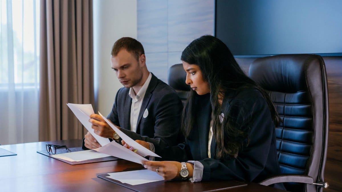Two business professionals in a conference room engaged in a meeting and document review.