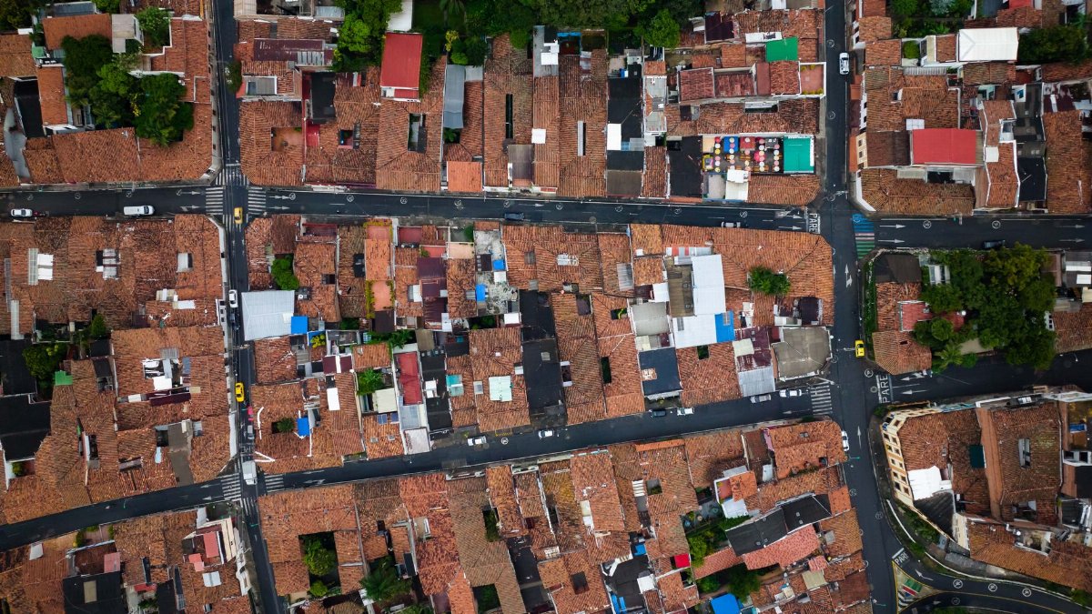Drone shot capturing a vibrant urban neighborhood with intersecting streets and red-tiled rooftops.