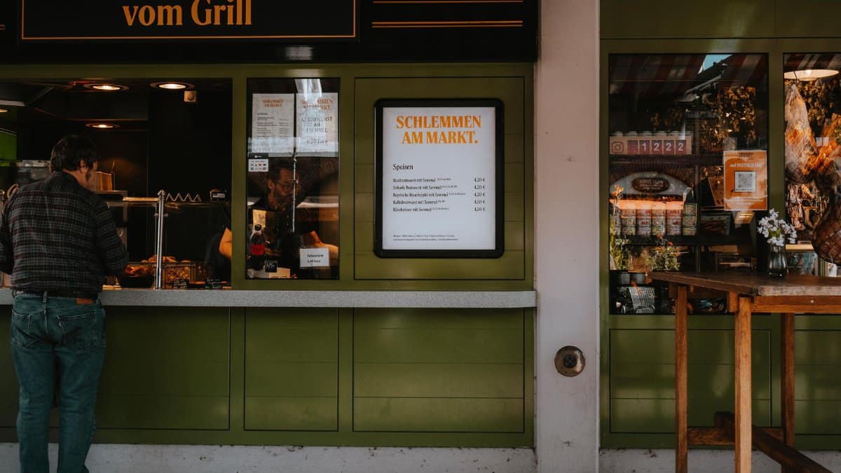 Cozy market stall with vibrant signage and customer in a bustling European street.
