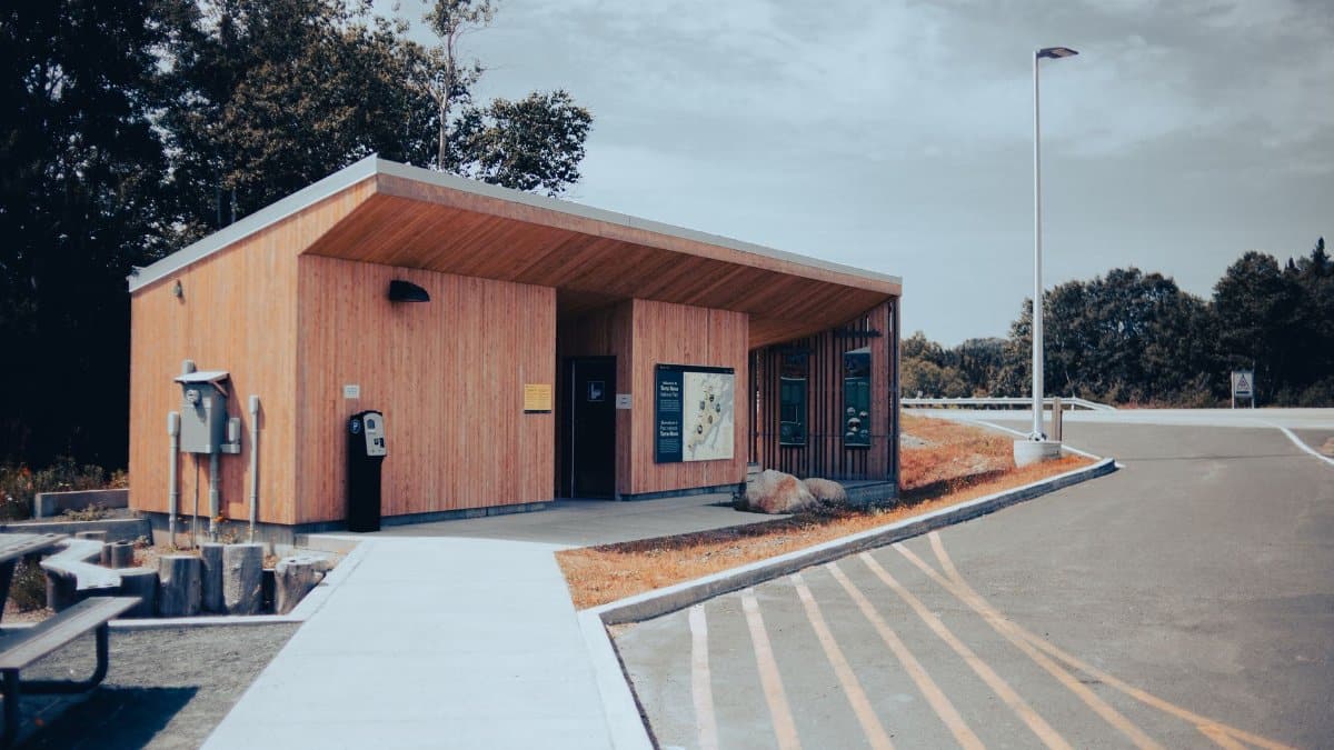 A wooden building at a roadside rest area with parking and a clear blue sky.