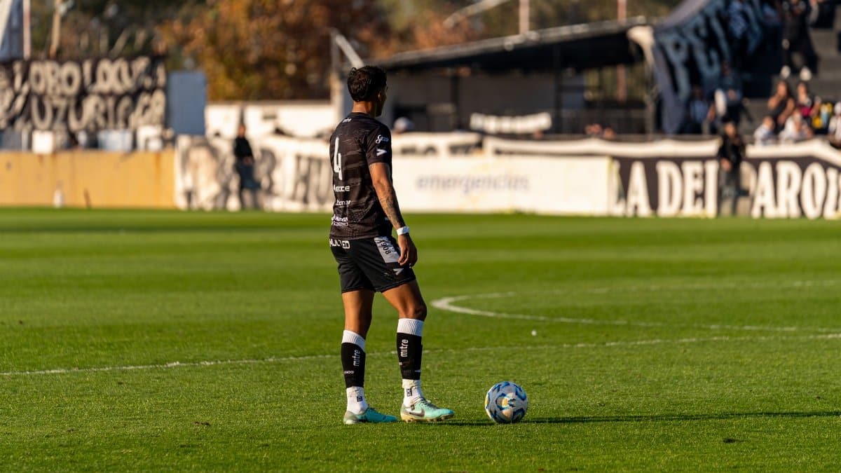 A soccer player in action during a match on a sunny day, ready to make a move.
