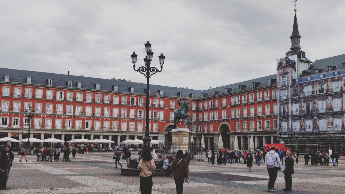 A bustling scene at Plaza Mayor in Madrid featuring the Philip III equestrian statue.