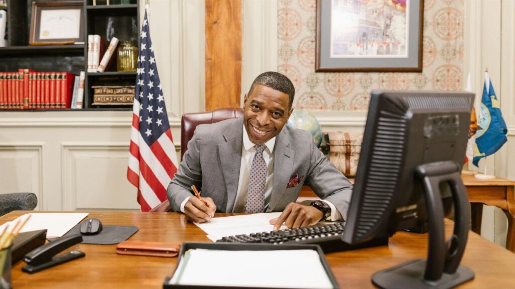 A lawyer in corporate attire smiling at a desk in a law office, displaying professionalism.