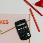 Flat lay image featuring a calculator, pens, and a folder labeled 'TAXES', perfect for finance-related themes.