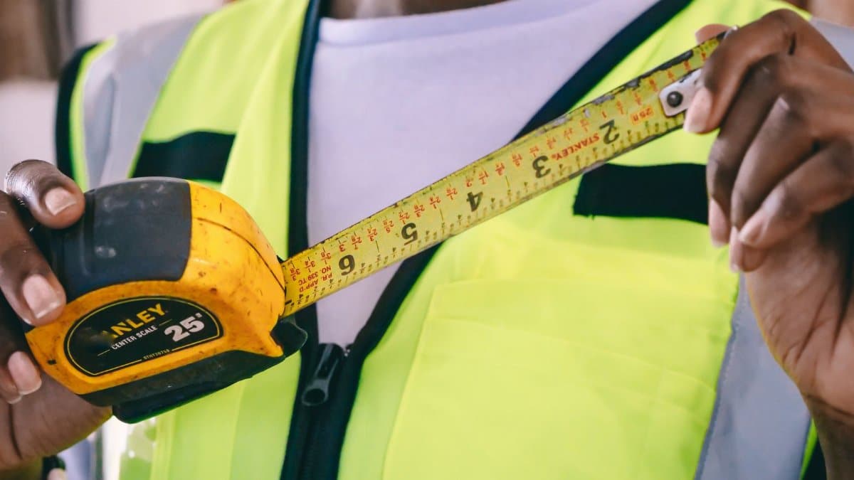 Detail of hands holding a measuring tape in a work environment.