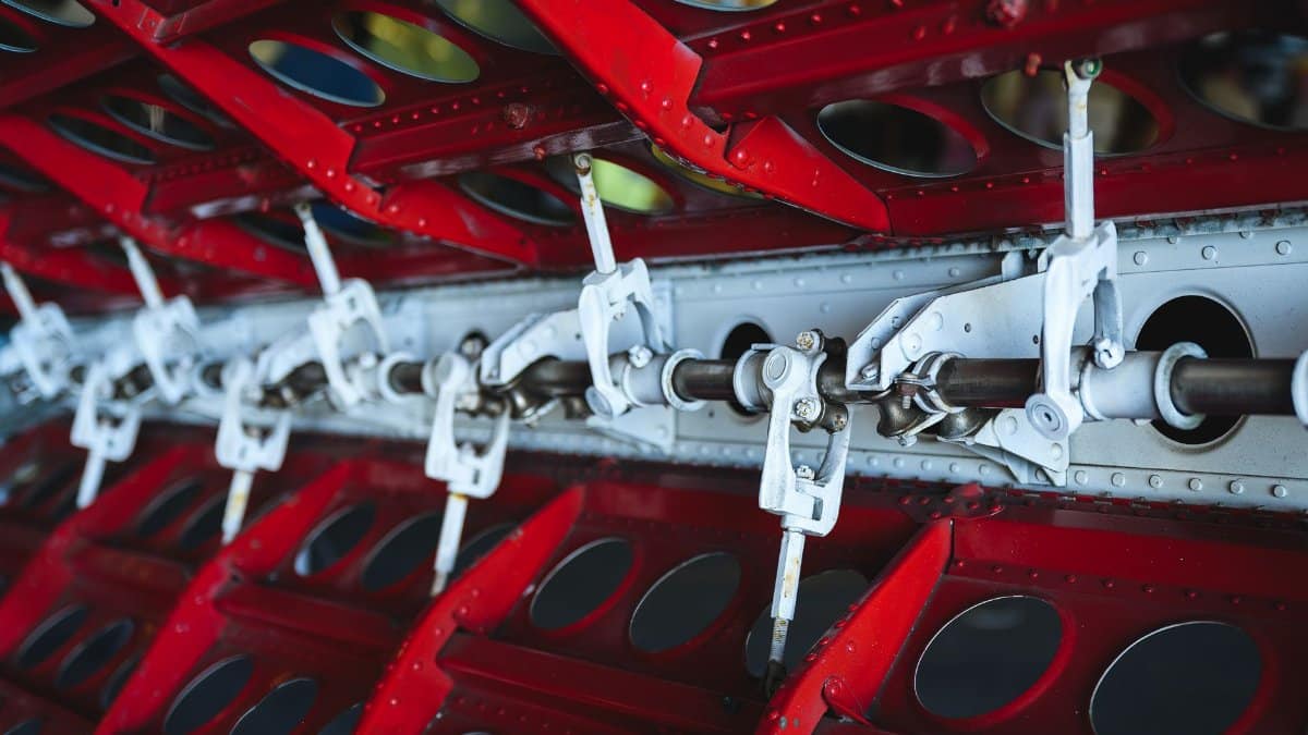 Close-up view of aircraft wing mechanism showcasing metal levers and vibrant colors.