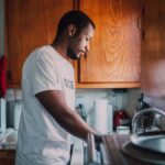 A man and woman volunteer wash dishes in a kitchen, helping their community.