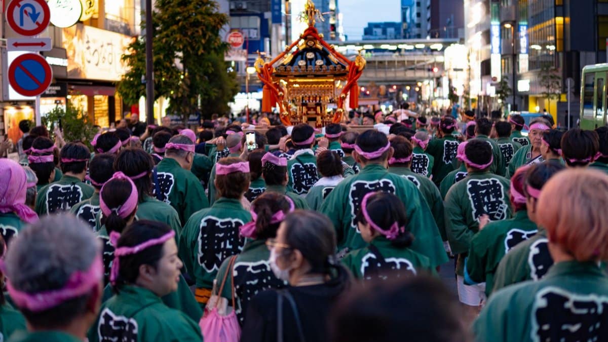 Crowd participating in a colorful traditional Japanese street festival with mikoshi parade.