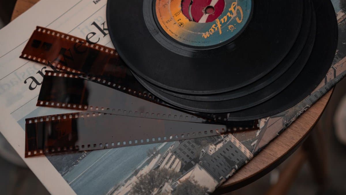 Stack of vintage vinyl records and film negatives on a wooden table.