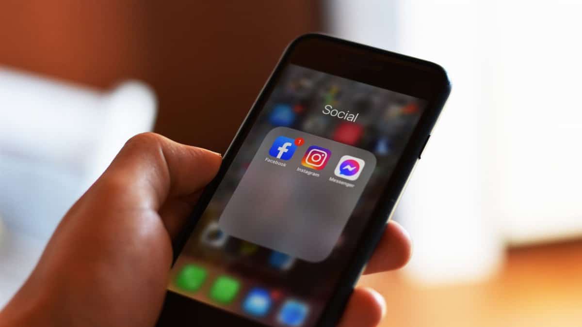 Close-up of hand holding smartphone showing social media apps like Facebook and Instagram.