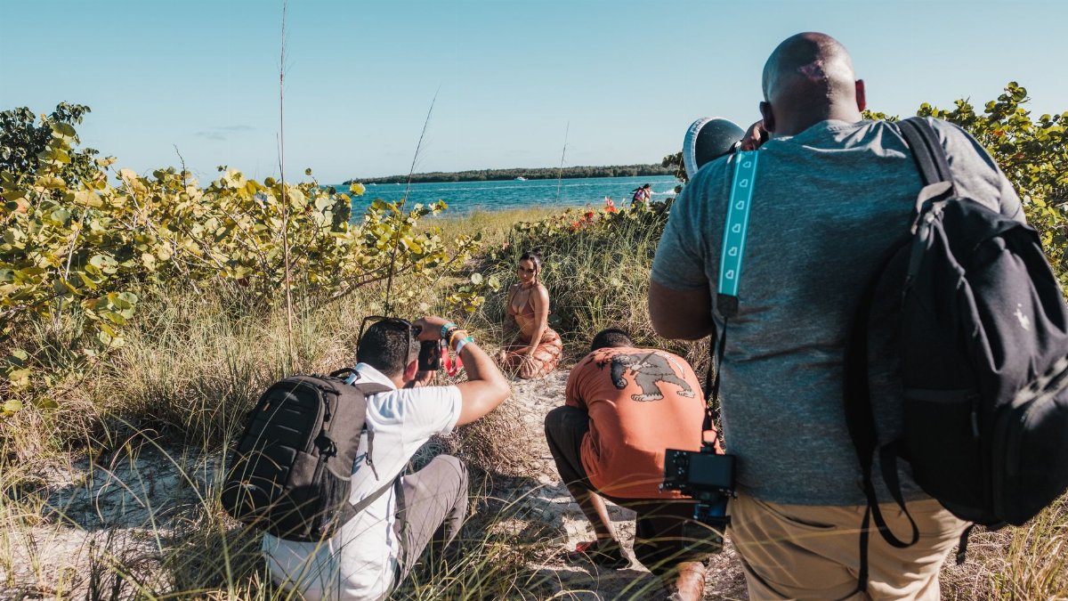 Behind-the-scenes of a beach photoshoot in Miami with photographers and a model.