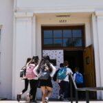 Group of students with backpacks entering a school building. Perfect for back-to-school themes.