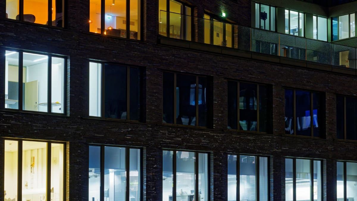 Night view of a modern office building facade with illuminated windows showcasing varied interior lighting.