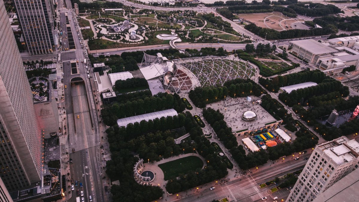 Stunning aerial view of Millennium Park and downtown Chicago cityscape at sunset, showcasing modern architecture and urban greenery.