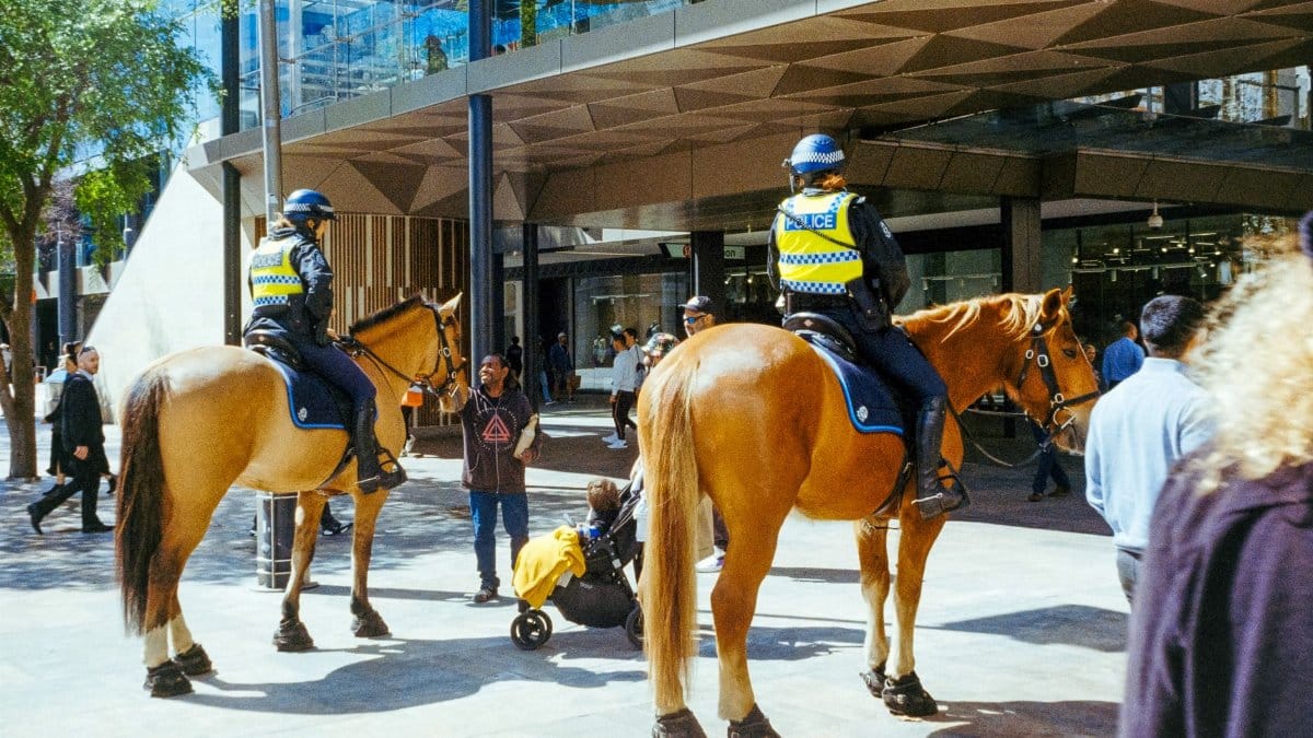 Two mounted police officers on patrol in a bustling urban street area.