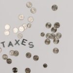 A visually striking flatlay of coins with 'Taxes' text on a white surface, ideal for financial concepts.