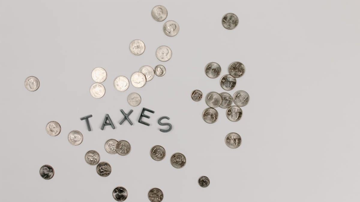 A visually striking flatlay of coins with 'Taxes' text on a white surface, ideal for financial concepts.