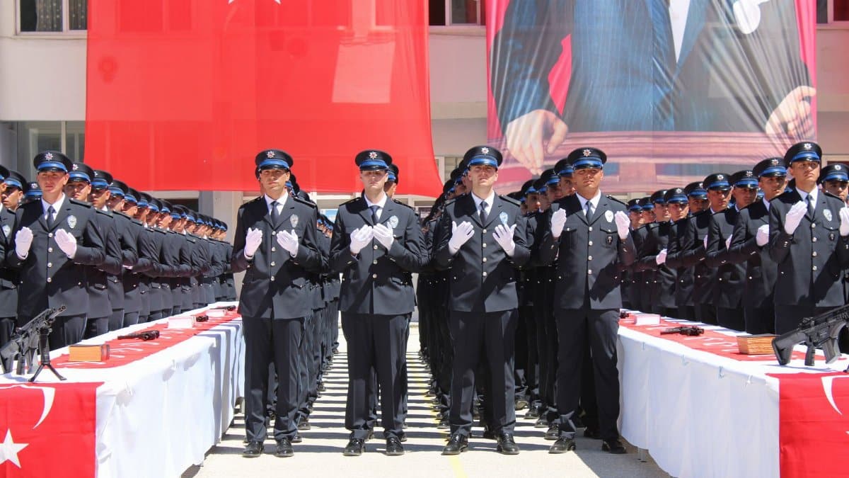 Police officers in uniform at a graduation ceremony in Yozgat, Türkiye with Turkish flags displayed prominently.