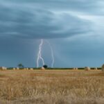 A striking image of lightning illuminating a rural hayfield under a stormy sky.