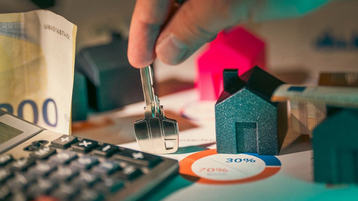 A close-up of real estate financial planning with keys, calculator, and money.