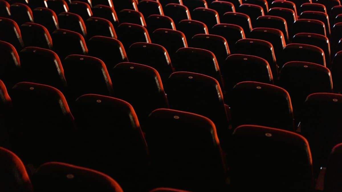 A view of empty red theater seats lit softly, showcasing the quiet ambiance of a cinema.