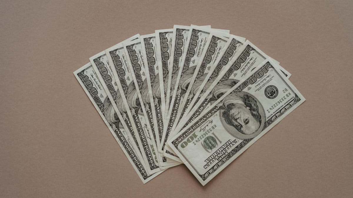 A neat arrangement of US dollar banknotes laid out in a fan shape on a brown surface.