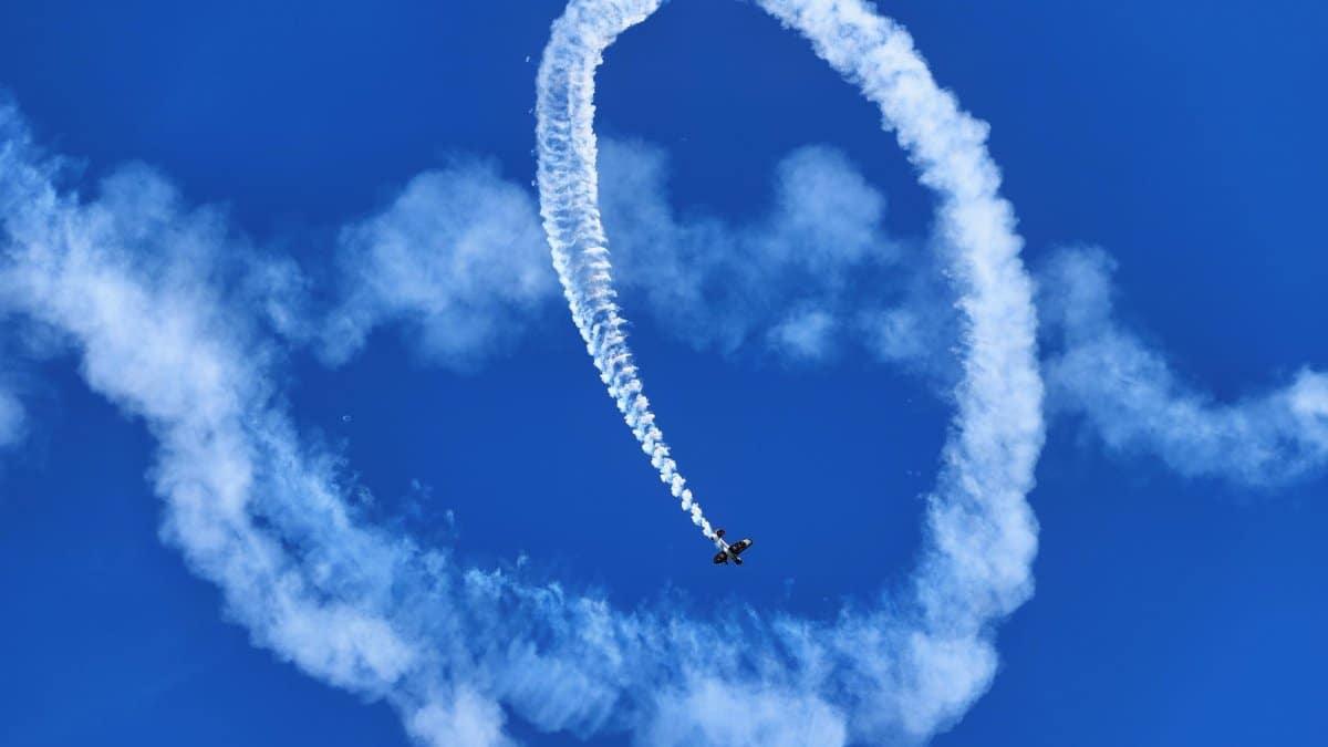 A vibrant blue sky with a stunt plane executing a thrilling aerobatic loop, leaving dramatic smoke trails.