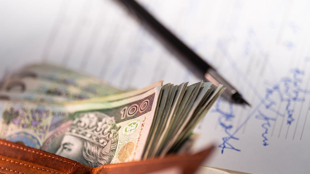 Stack of Polish zloty banknotes with pen and document, financial concept.