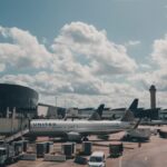 A United airplane parked on the airport apron under a scenic cloudy sky.
