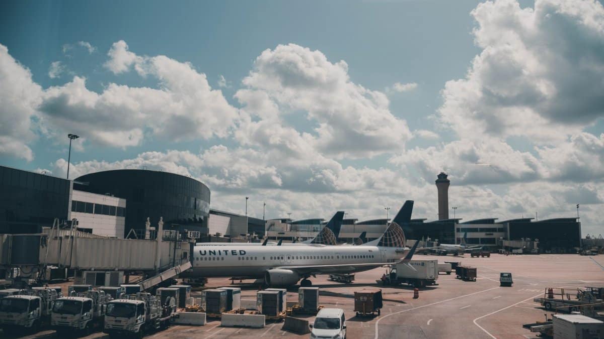 A United airplane parked on the airport apron under a scenic cloudy sky.