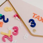 Bright plastic numbers scattered over a tax envelope, symbolizing accounting and finance concepts.