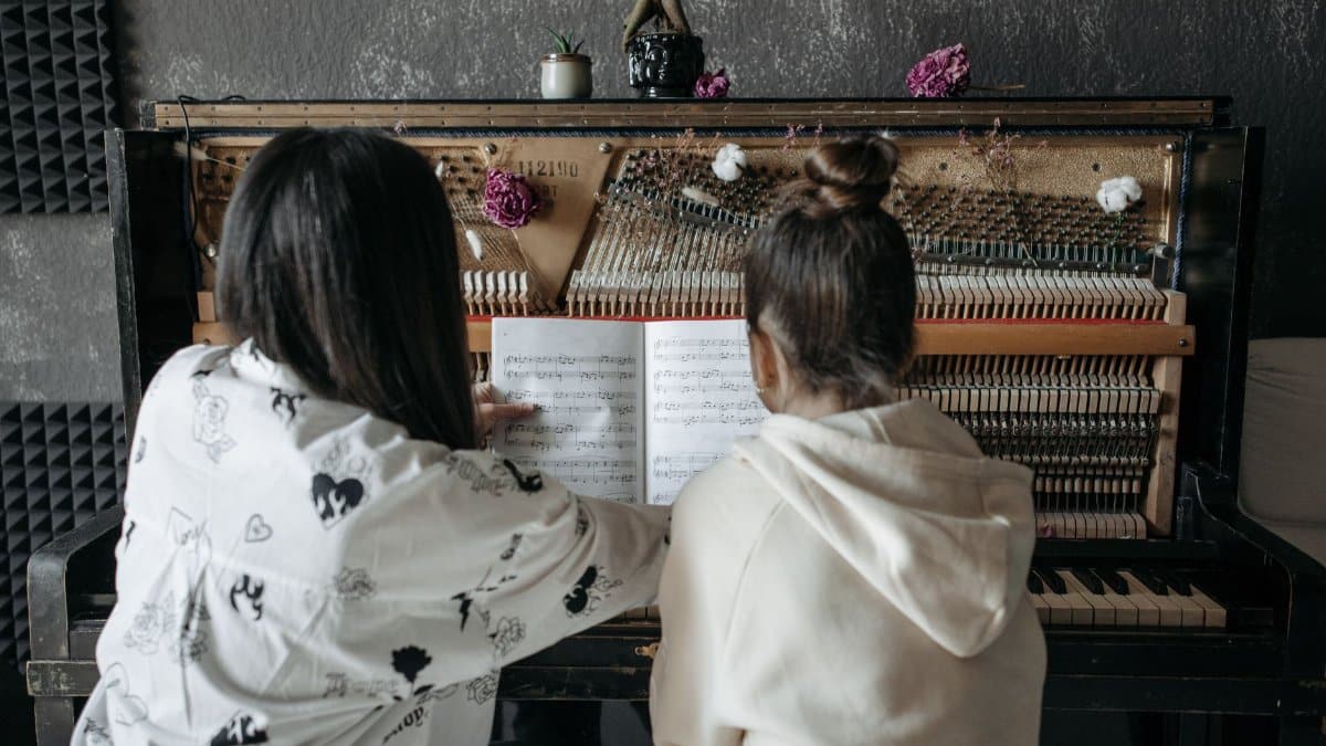 Back view of a piano lesson featuring a teacher guiding a student on music notation.