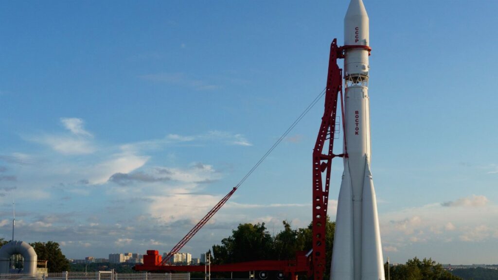 Vostok rocket stands poised on launch pad under clear blue sky at space center.