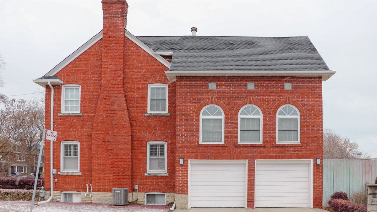 Red brick house exterior in Toronto with arched windows, chimney, and double garage.