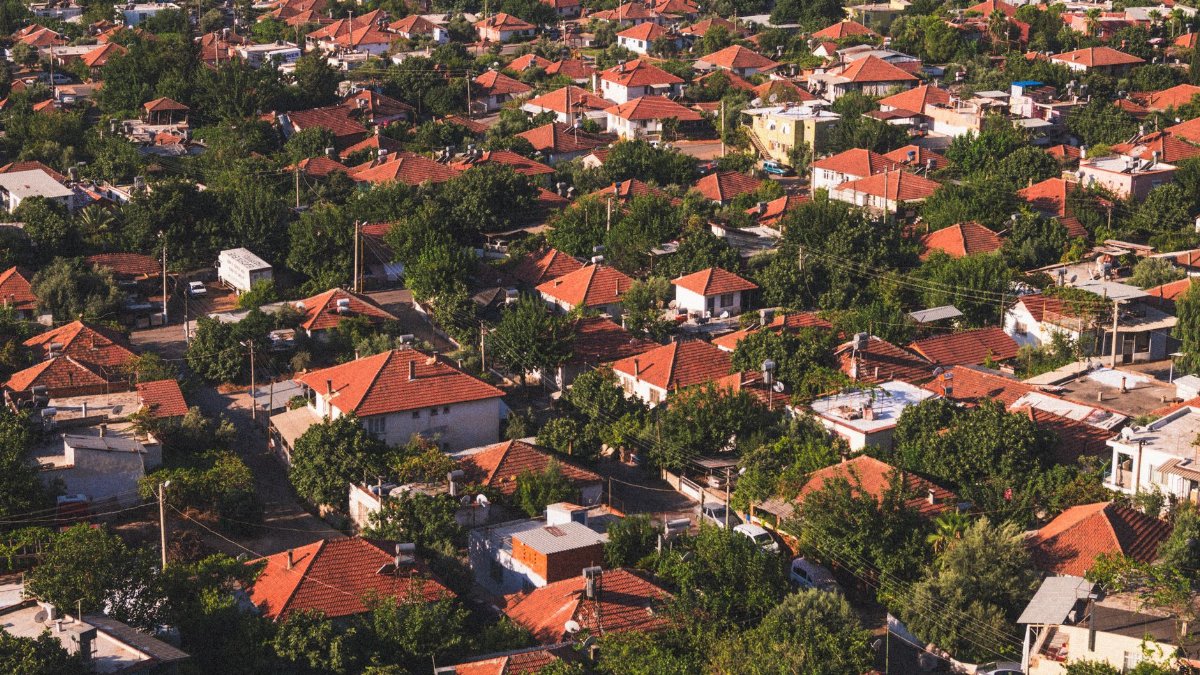 Vibrant aerial view of a suburban neighborhood with red-tiled roofs surrounded by lush greenery.