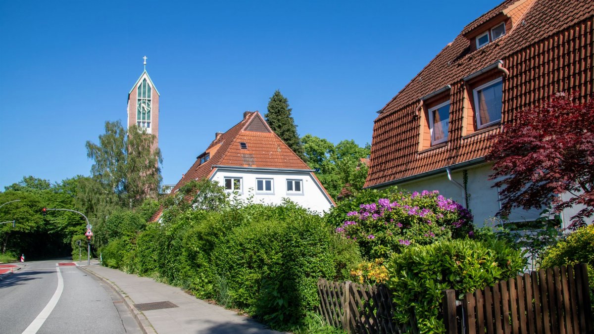 Picturesque residential street in Hamburg with a church tower and lush greenery.