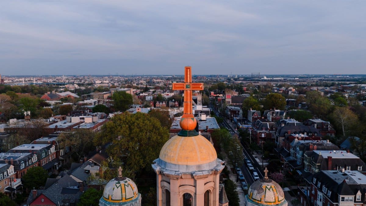 Aerial view of a Philadelphia neighborhood featuring a church dome with a cross at sunset.