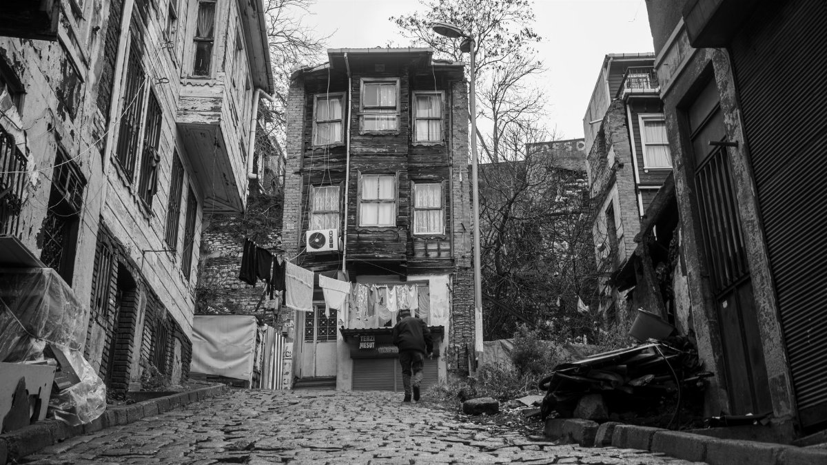 Black and white photo of a cobblestone street with old buildings and laundry hanging, conveying a nostalgic urban feel.