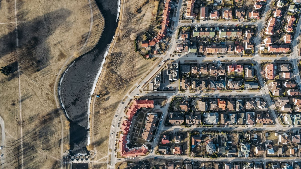 Drone shot of a suburban residential area with roads and houses alongside a river.