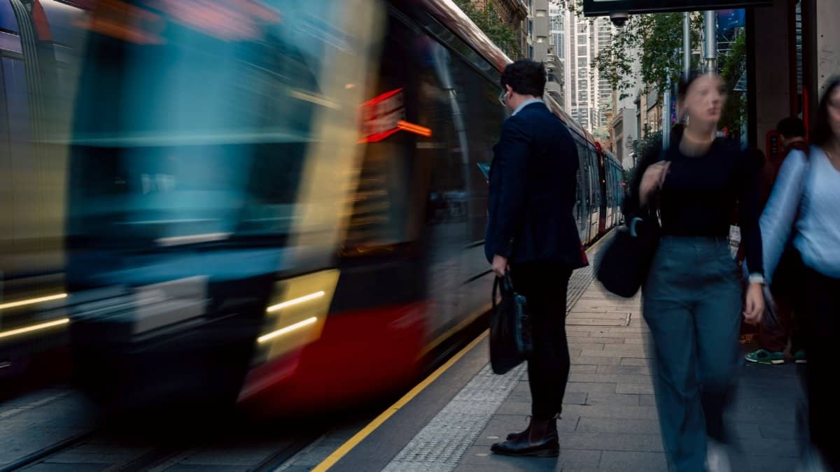 Blur of people and train at a Sydney light rail station capturing city life and motion.