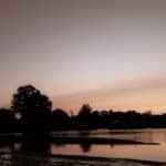 Tranquil sunrise scene in Stamford, CT, displaying calm waters and silhouetted trees.